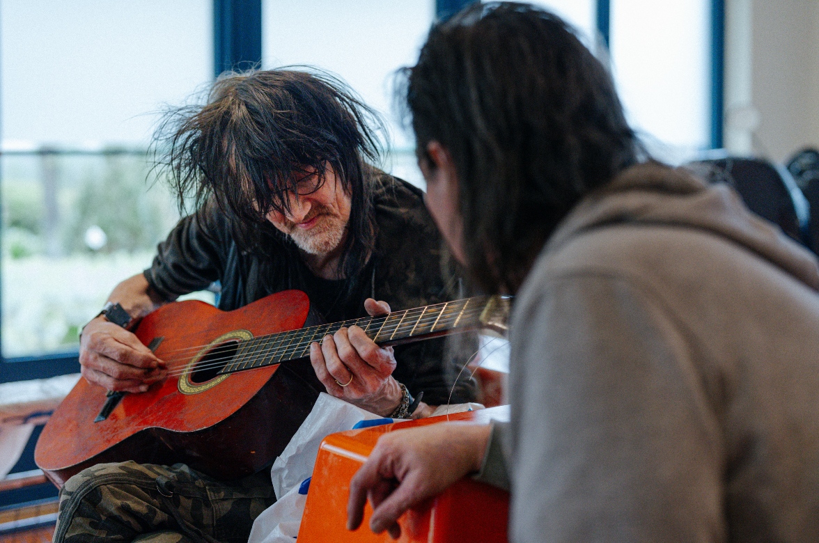 Client speelt gitaar en hulpverlener luistert